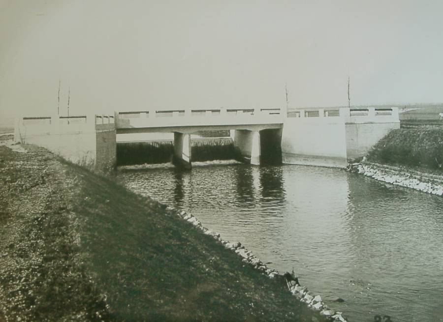 Flutwehr mit Heuwegbrücke bei Petershausen.<br>Die historische Aufnahme von 1924 zeigt ganz deutlich das künstlich bei der Regulierung angelegte Flussbett der Glonn. Die Ufer sind sehr steil und künstlich befestigt. Die Flusssohle wurde tiefer gelegt.